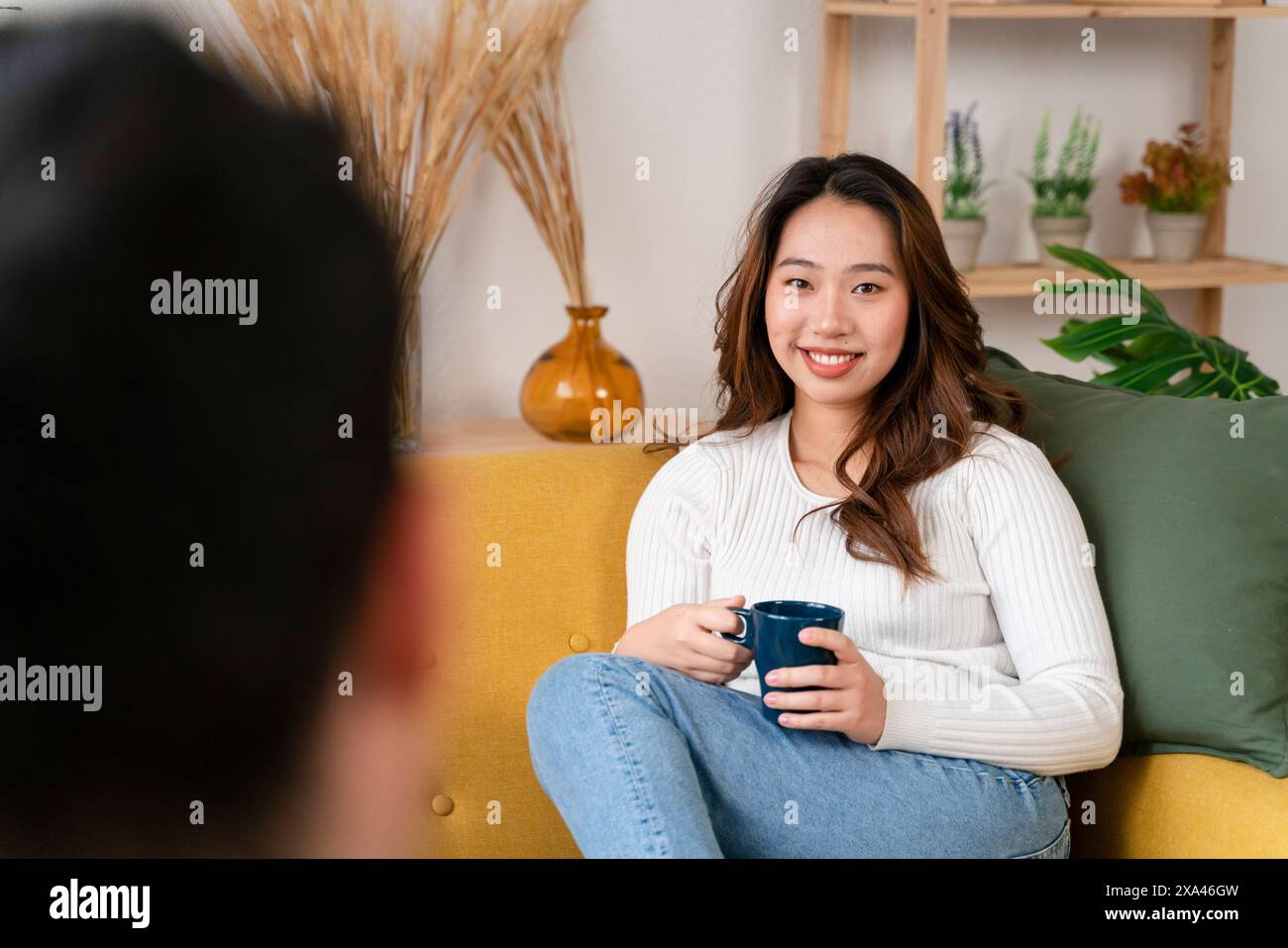 Woman smiling on couch holding a cup Stock Photo