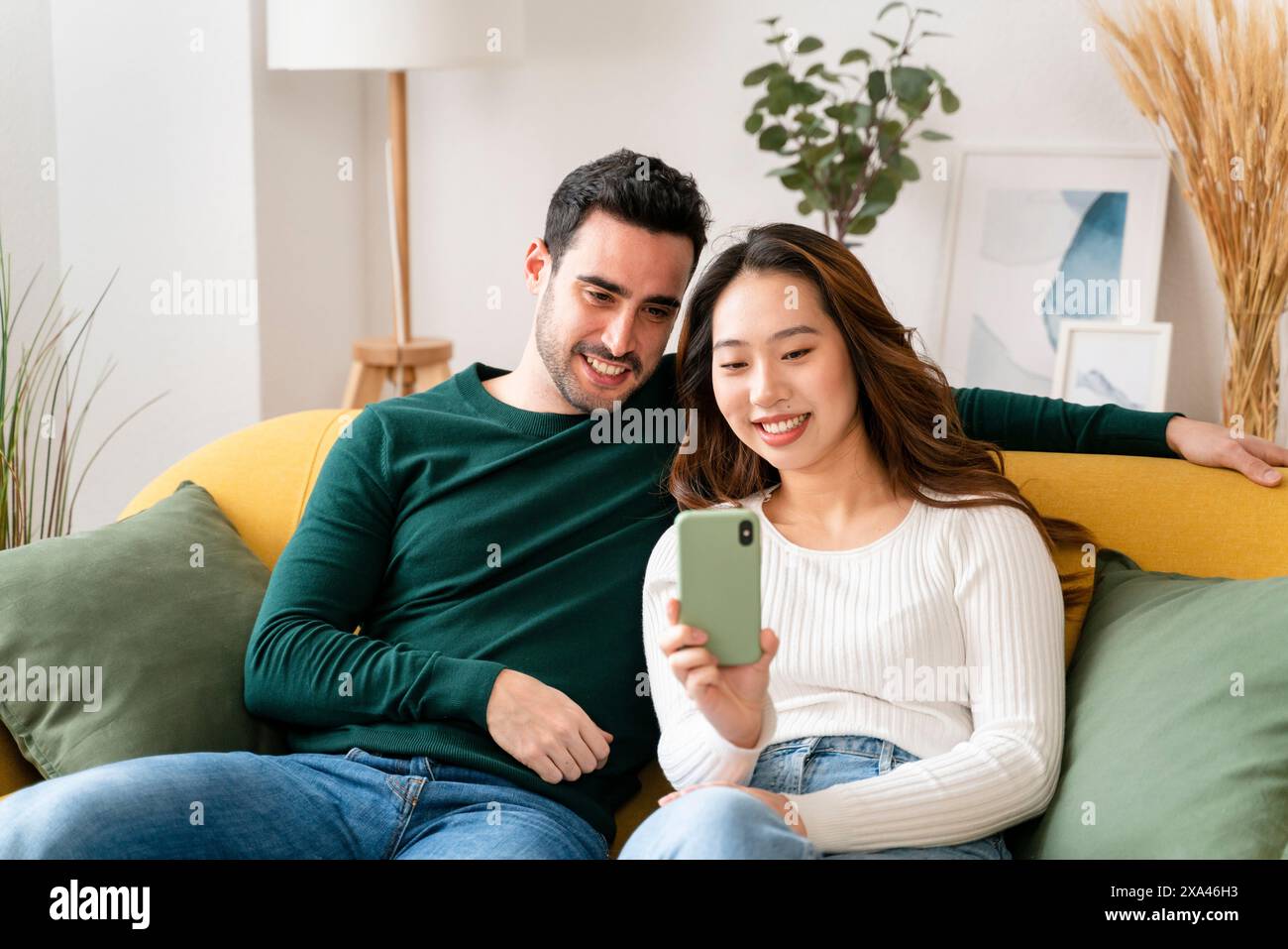 Couple looking at a smartphone on a couch. Stock Photo