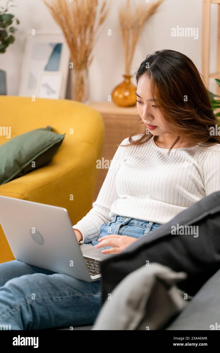 Woman working on laptop while sitting on a couch Stock Photo