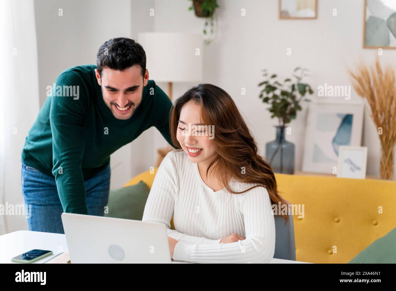 Two people smiling and looking at a laptop screen. Stock Photo