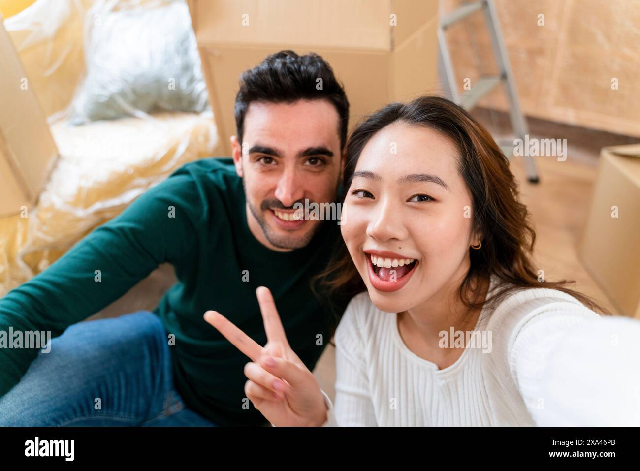 Couple smiling and taking a selfie during a moving day. Stock Photo