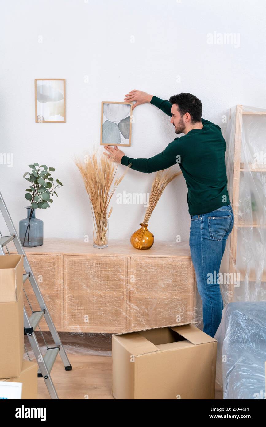 Man arranging a picture frame in a room with moving boxes Stock Photo ...