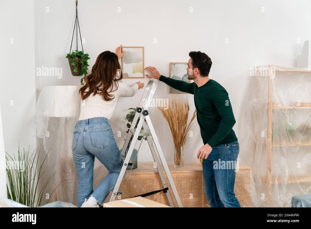 Couple arranging a picture frame on a wall Stock Photo