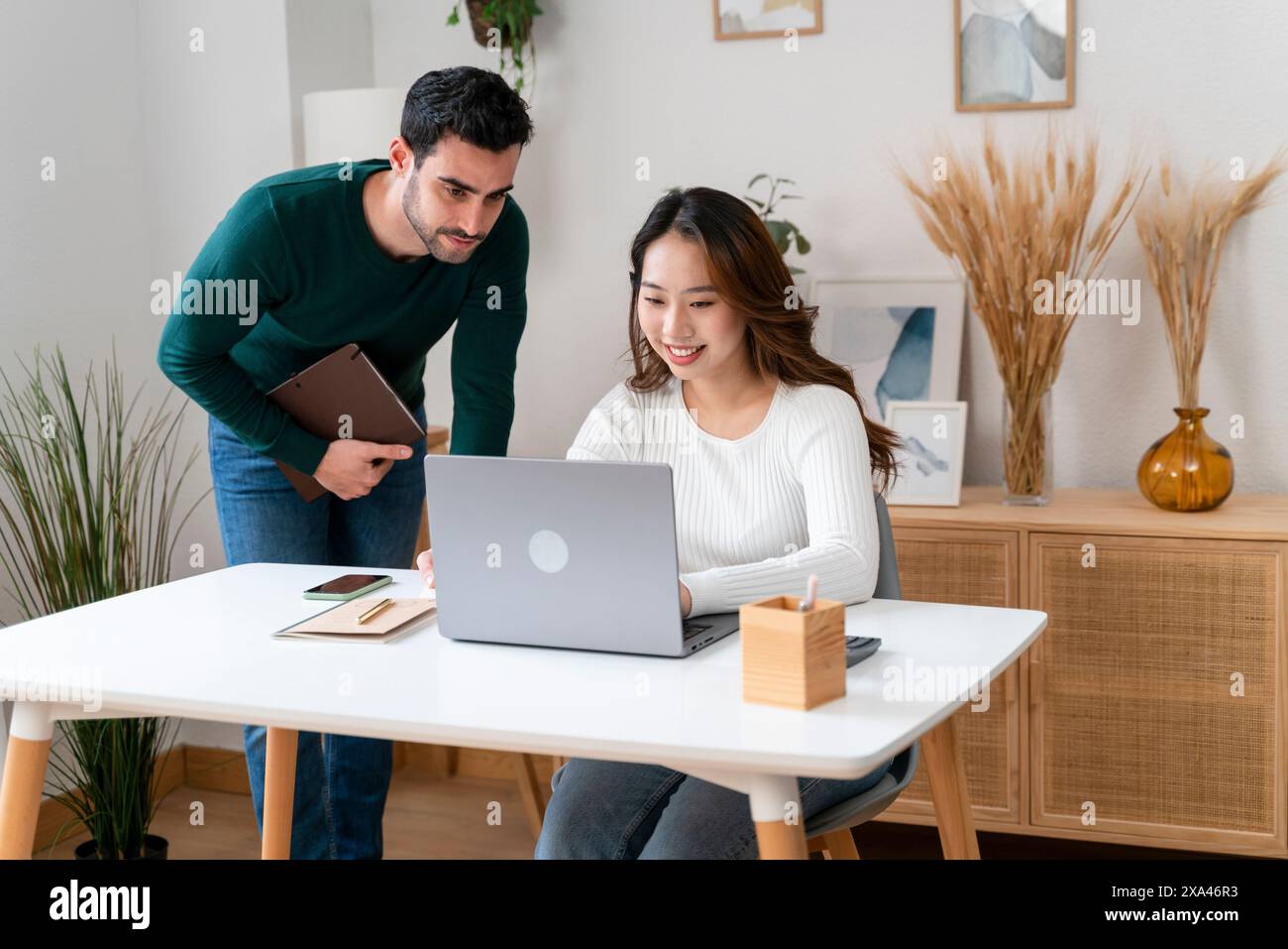 Two colleagues working on a laptop in a modern office. Stock Photo