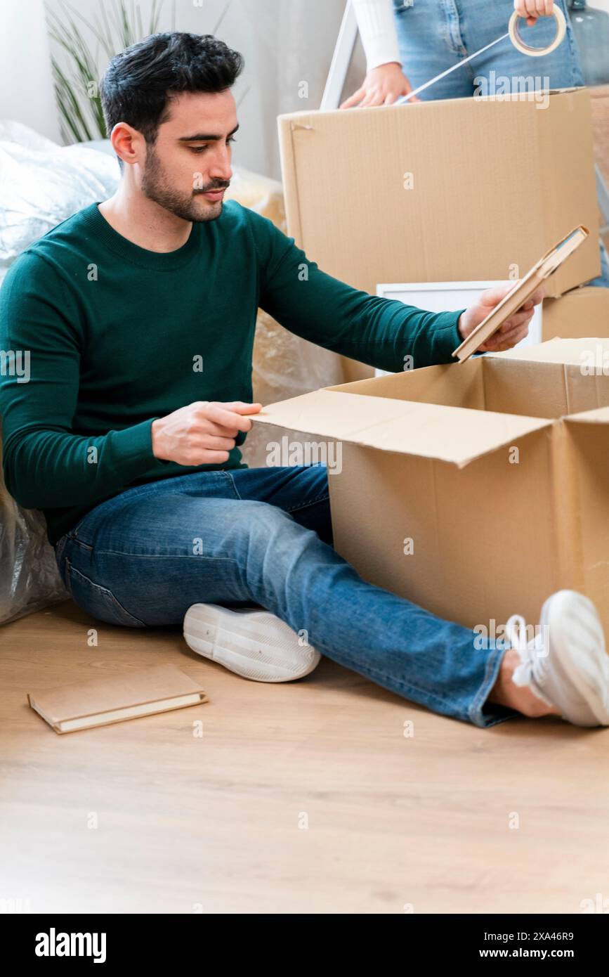 Man sitting on floor packaging items into a box Stock Photo