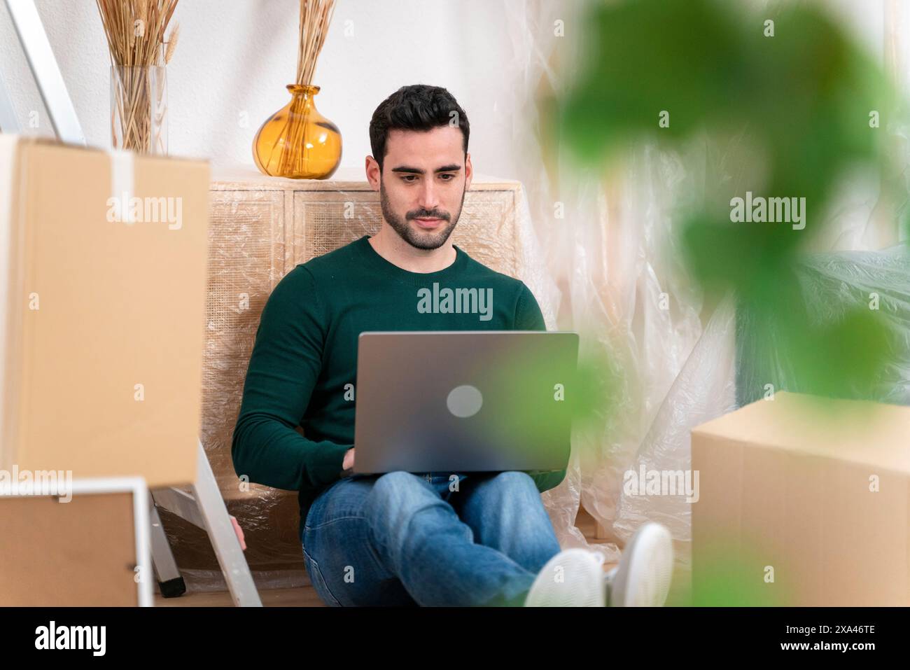 Man with laptop among moving boxes Stock Photo