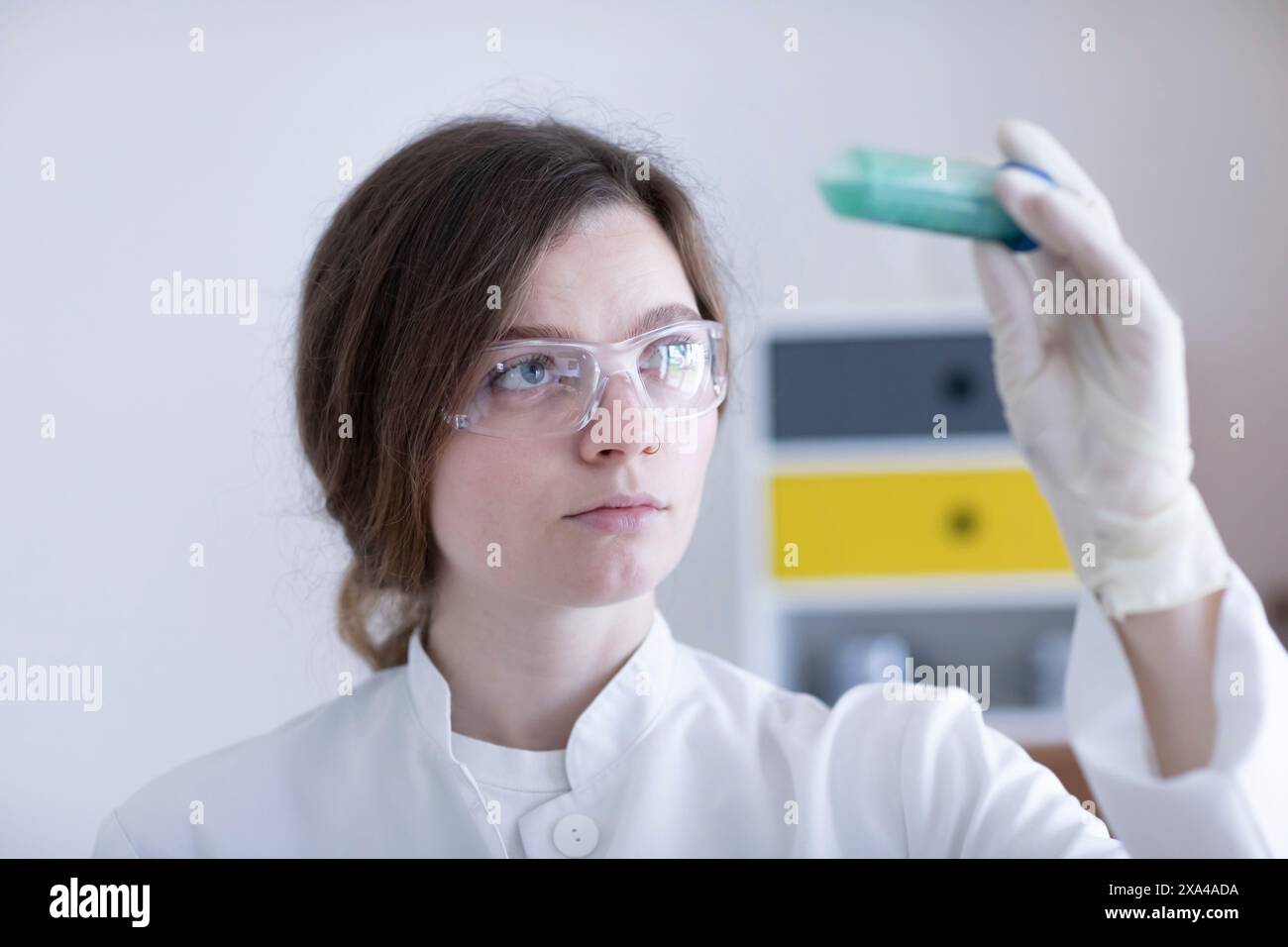 A focused scientist examines a test tube with a blue liquid in a ...