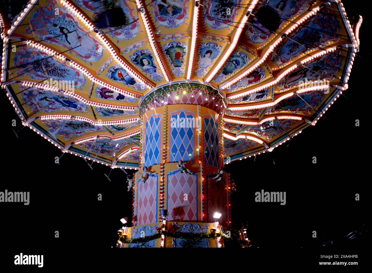 A vibrant and illuminated swing ride at night, with its chairs in ...