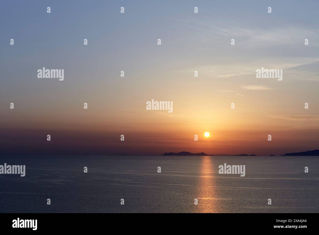 Sunset over a calm sea with islands silhouetted against the sky. Stock Photo