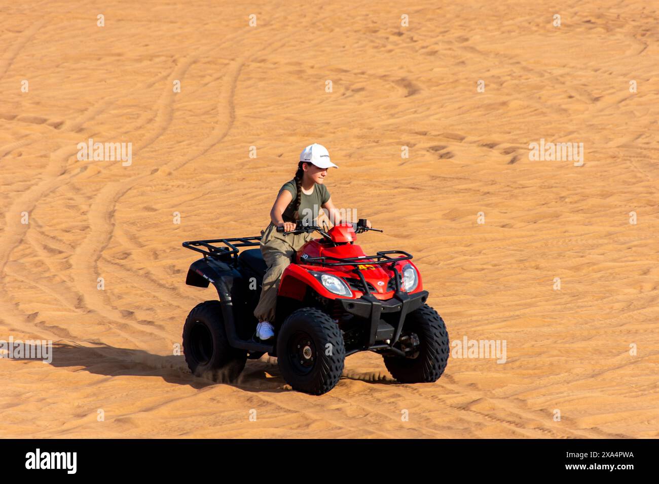 Tourist riding an ATV across expansive sandy terrain in the Dubai ...