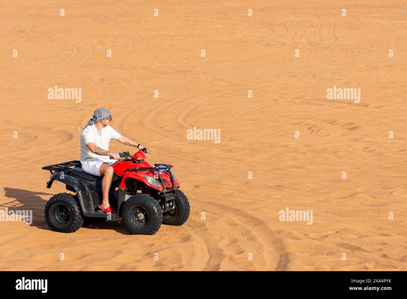 Tourist riding an ATV across expansive sandy terrain in the Dubai ...