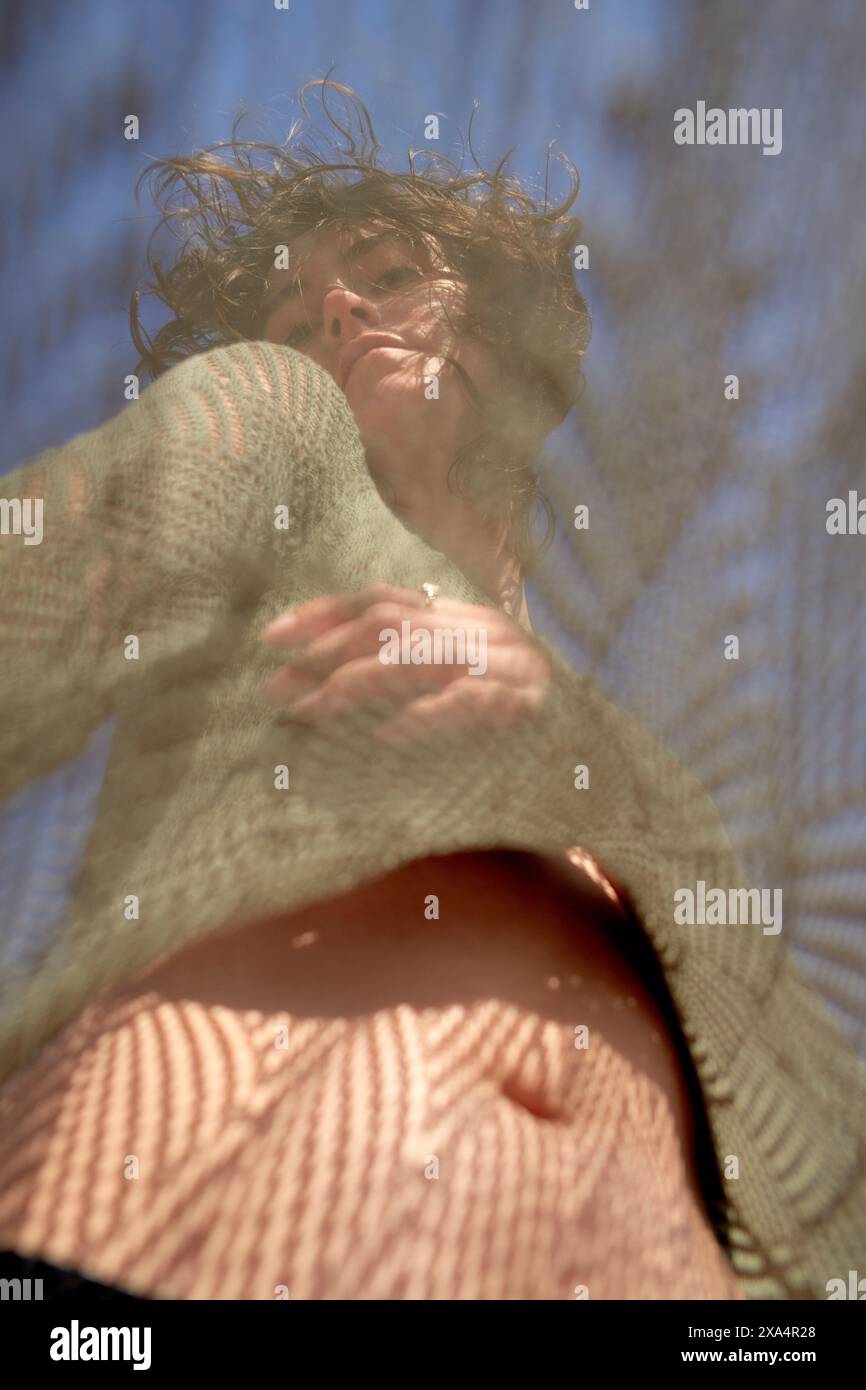 A person with wavy hair is seen through a translucent textured material ...