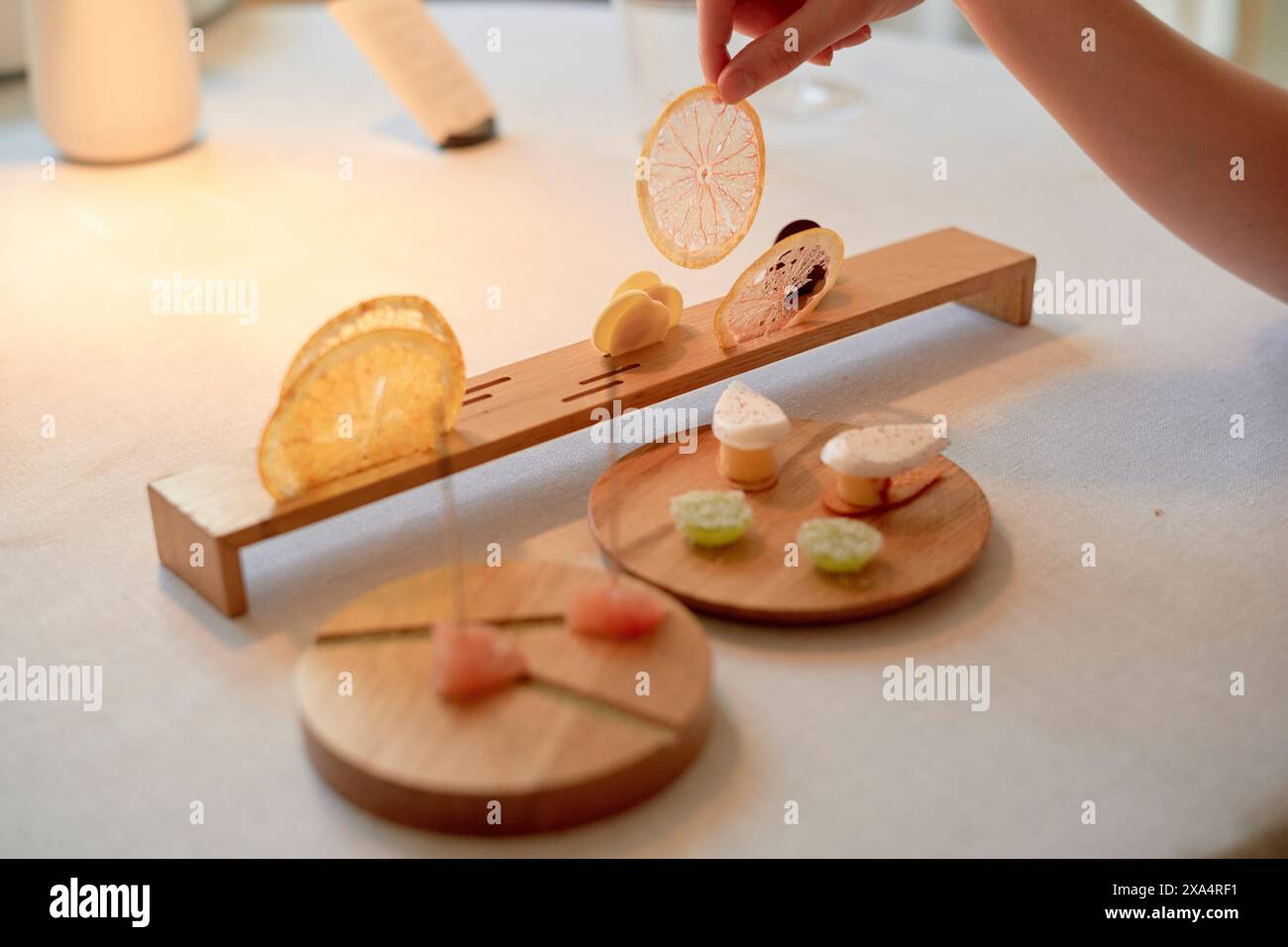 A hand arranging delicate gourmet bites on a wooden serving platter with precision. Stock Photo