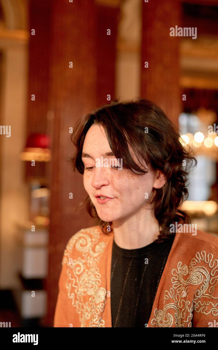 Smiling woman with closed eyes wearing a decorative jacket indoors. Stock Photo