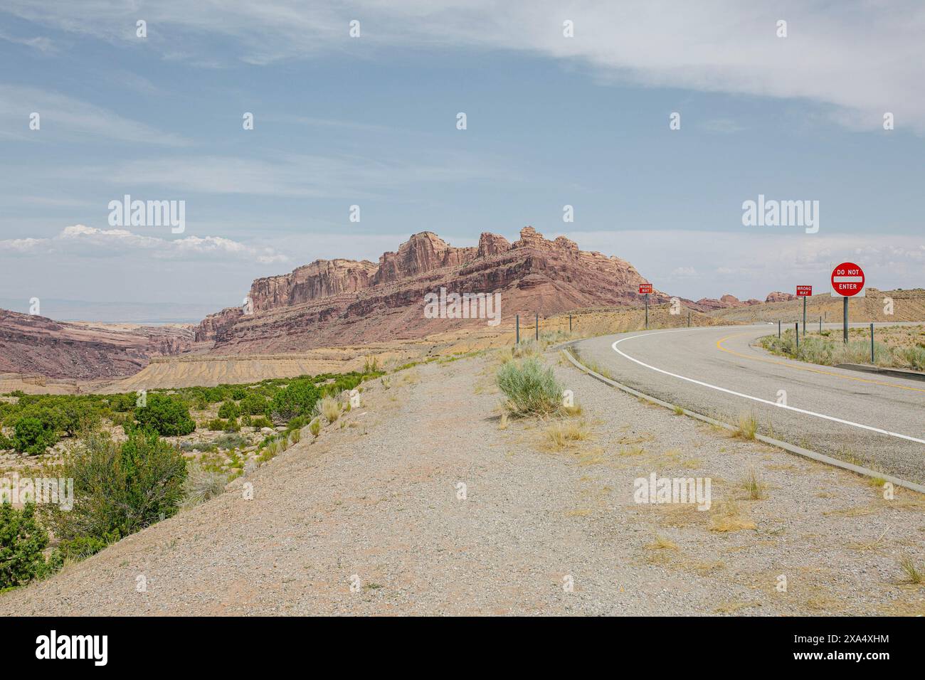 Rocky Rpad Sign Curving road leading towards rocky desert mountains under a clear blue ...