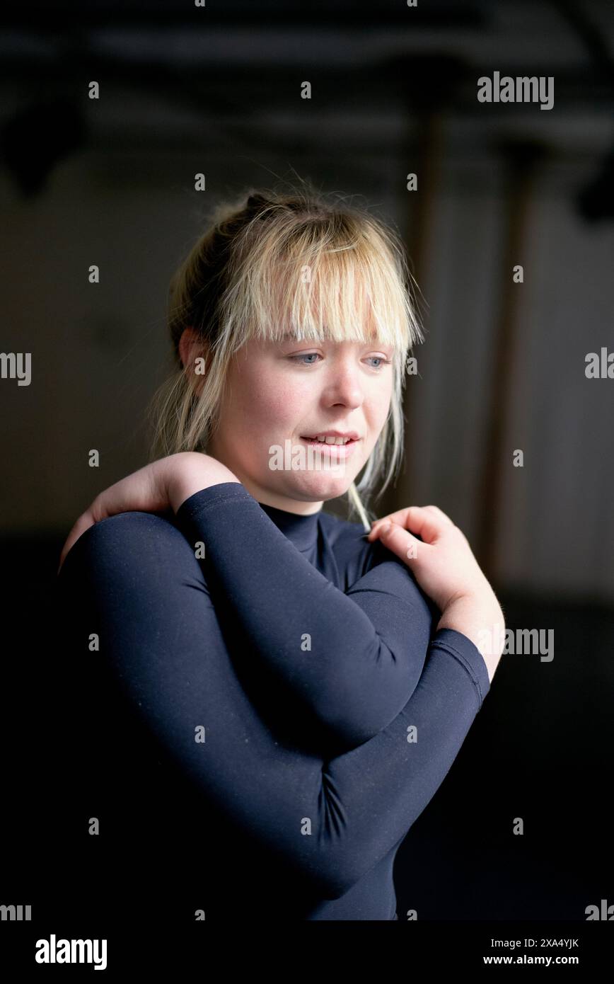 Woman stretching her arm before a workout in an indoor setting. Stock Photo