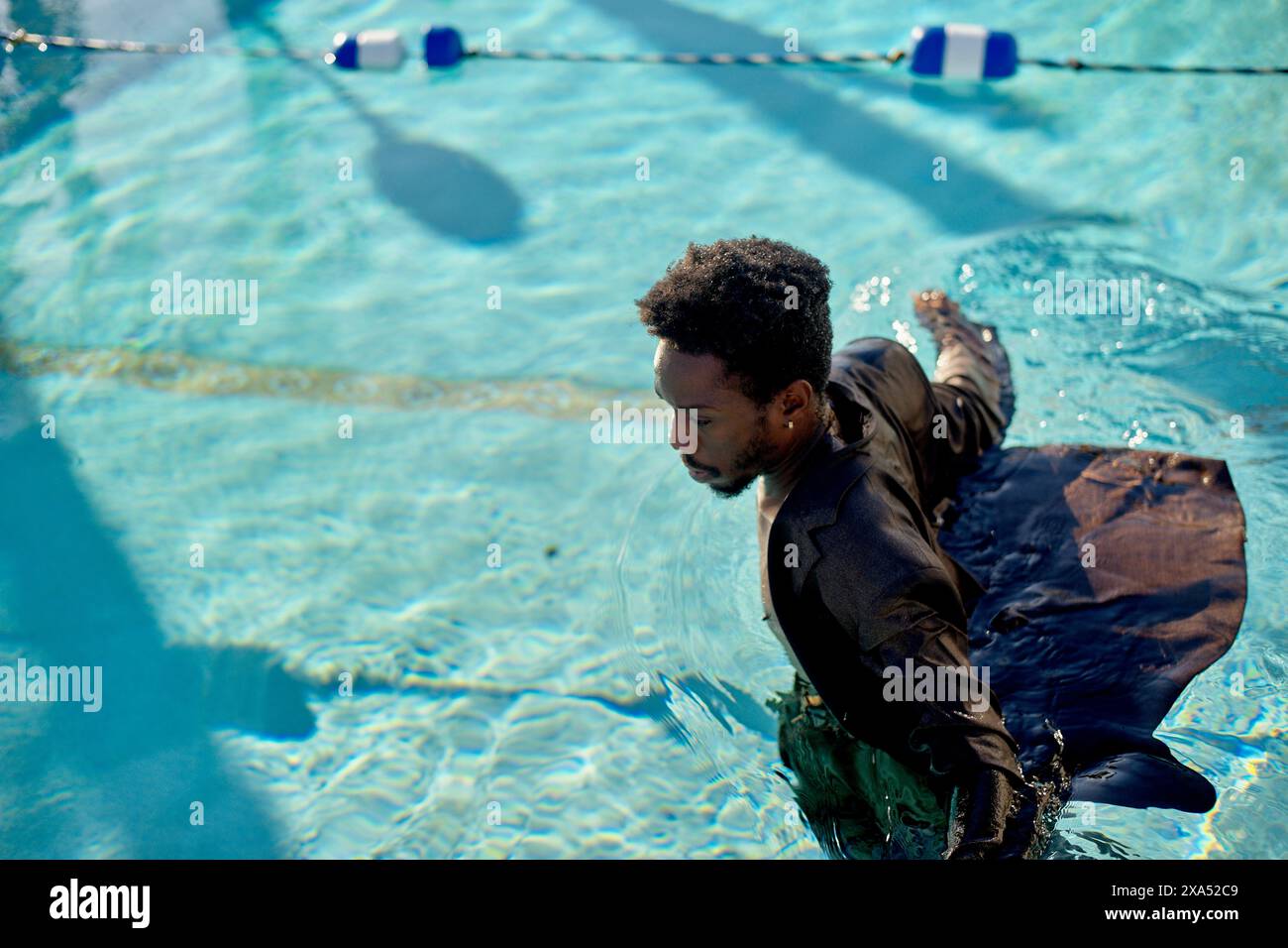 Man swimming in a pool with clothes on during a sunny day. Stock Photo
