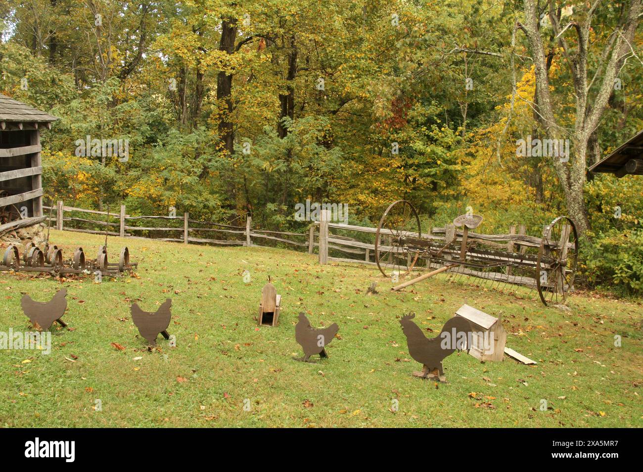 Old farm equipment and metallic chicken silhouettes displayed at the historical Johnson Farm in Virginia's Blue Ridge Parkway, USA Stock Photo