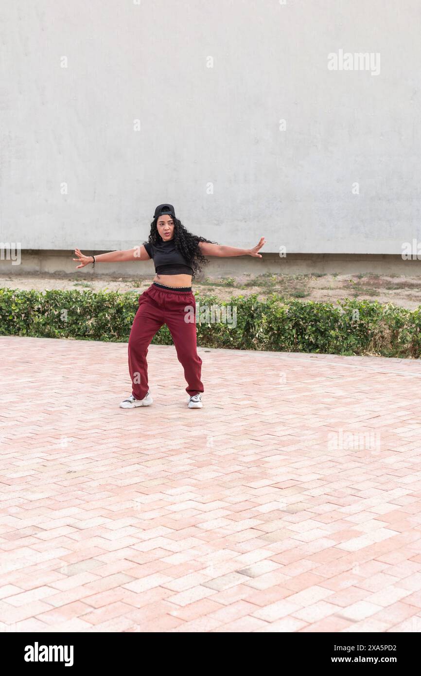 Young woman in casual athletic wear striking a hip-hop dance pose outdoors. Stock Photo