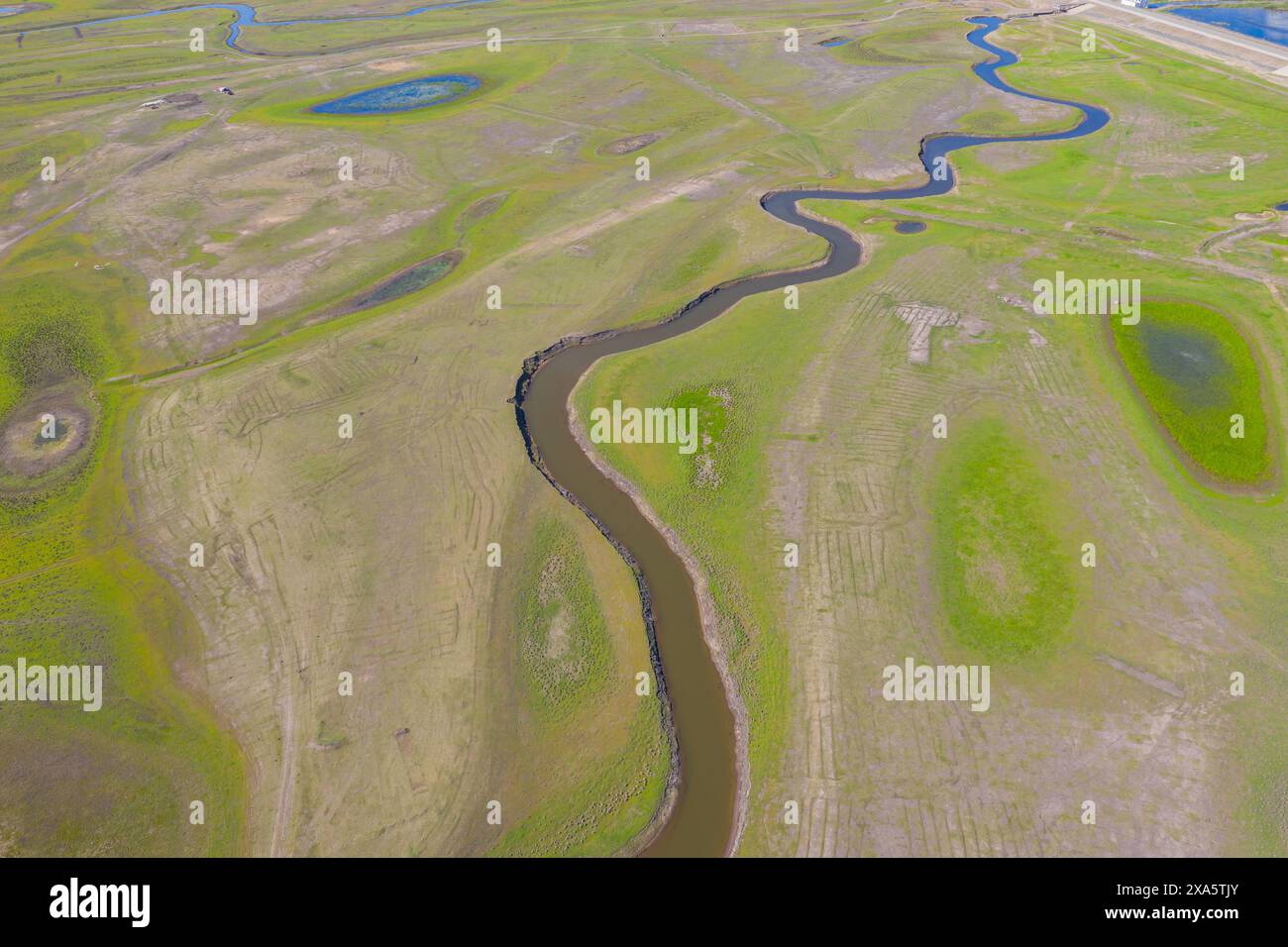 A tranquil landscape with grass, water, and sky Stock Photo