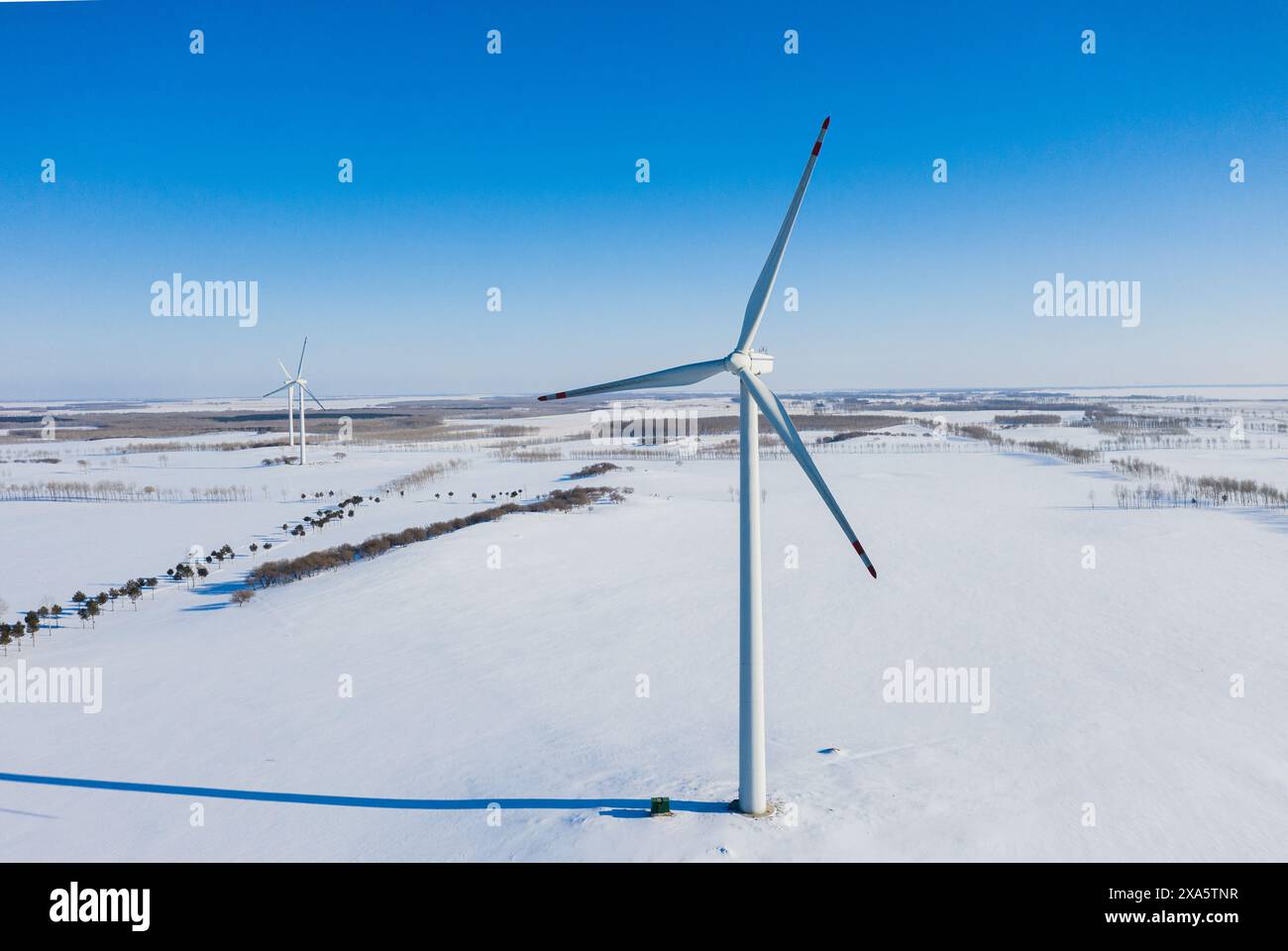 A wind turbine in snowy field under clear blue sky Stock Photo - Alamy