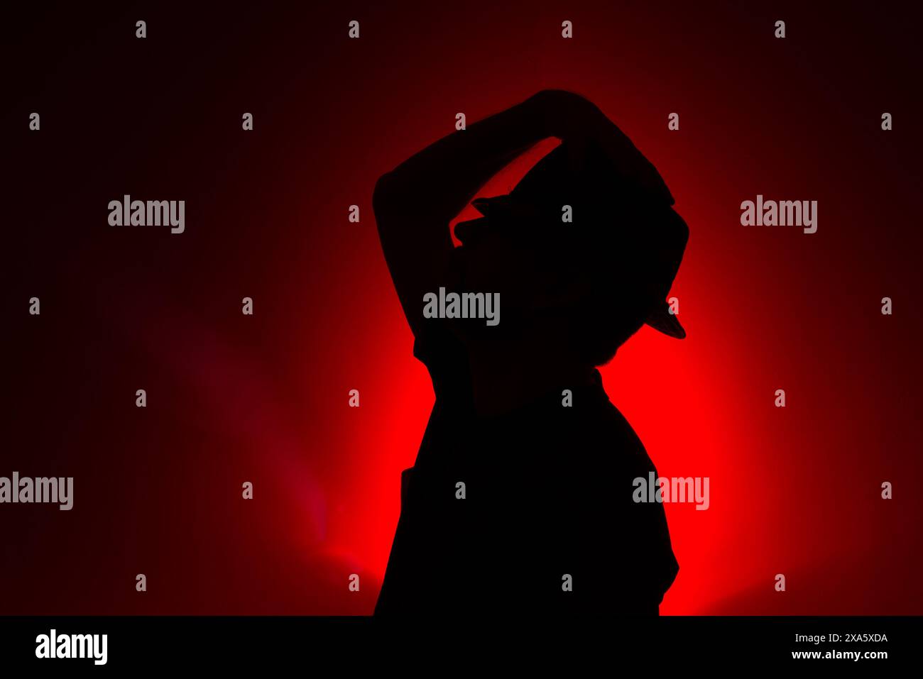 Studio portrait of a man holding hat in silhouette. Isolated on colored background. Stock Photo