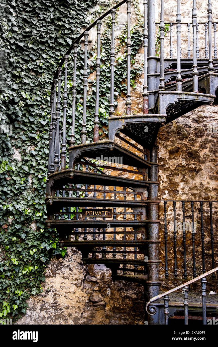 An antique iron spiral staircase with ornate railings, adjacent to a ...