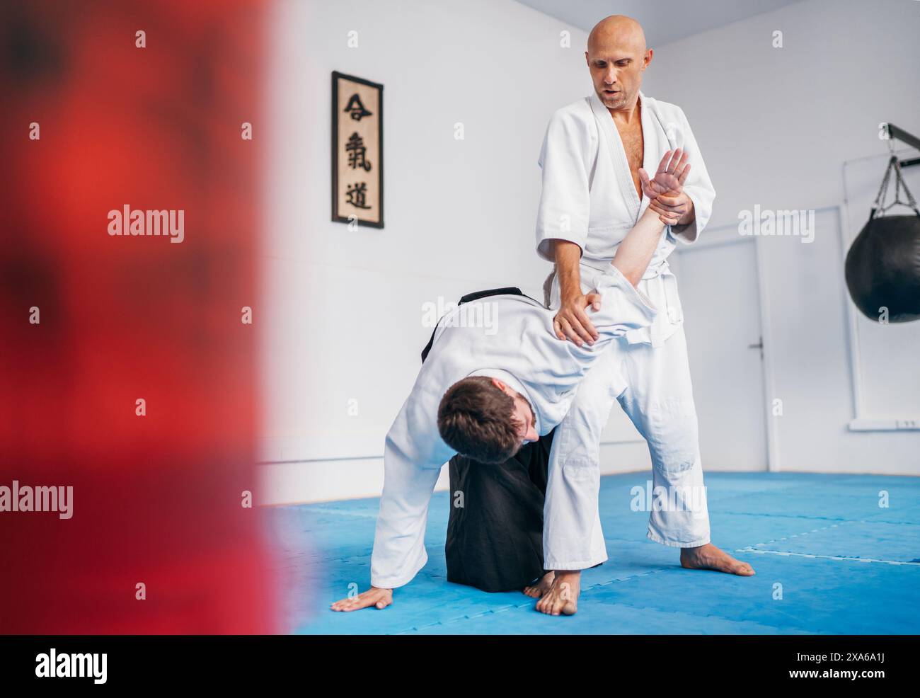 Two men train in aikido with one applying joint lock Hiji kime osae