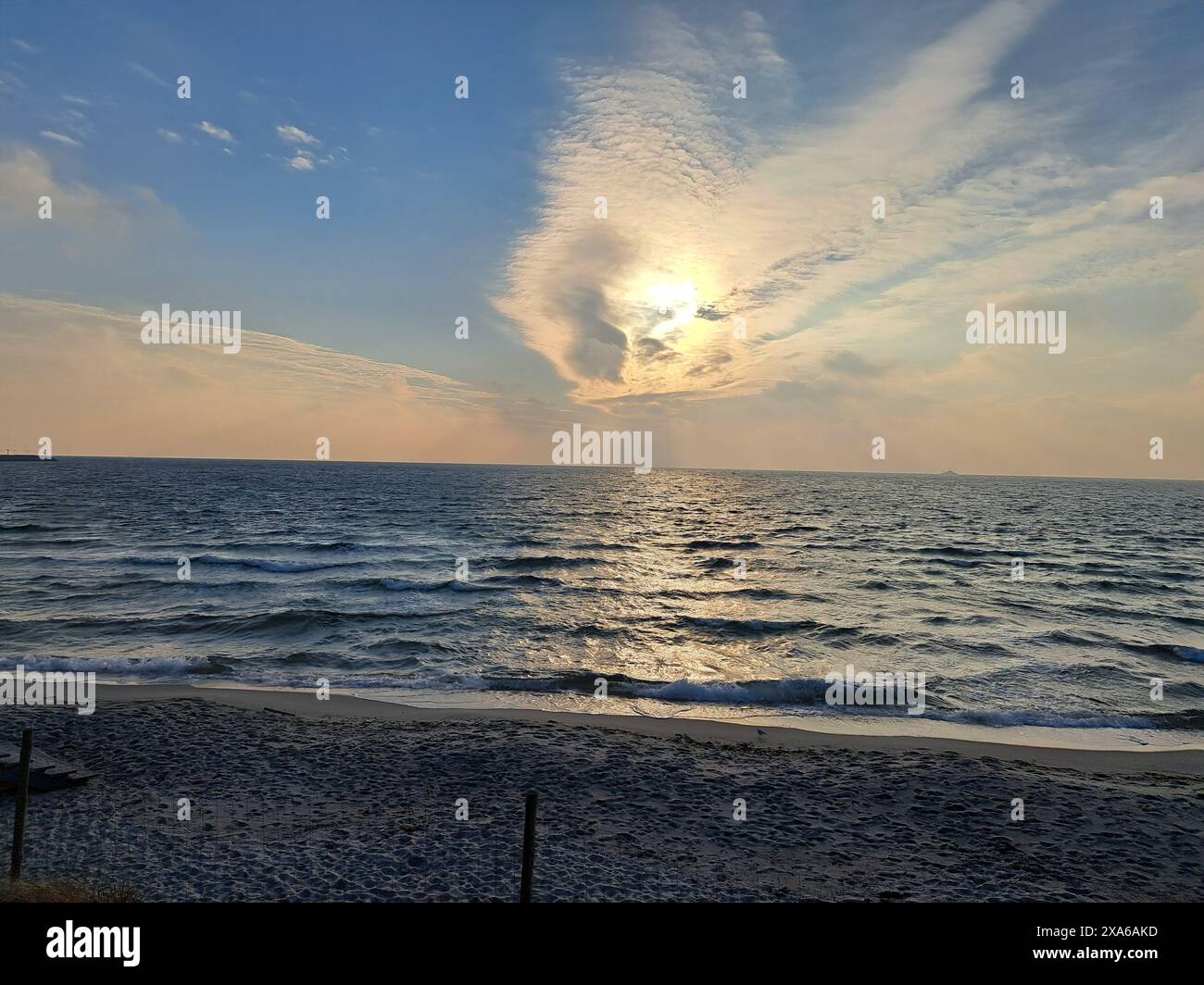 The Sun setting over calm waters at a deserted beach Stock Photo