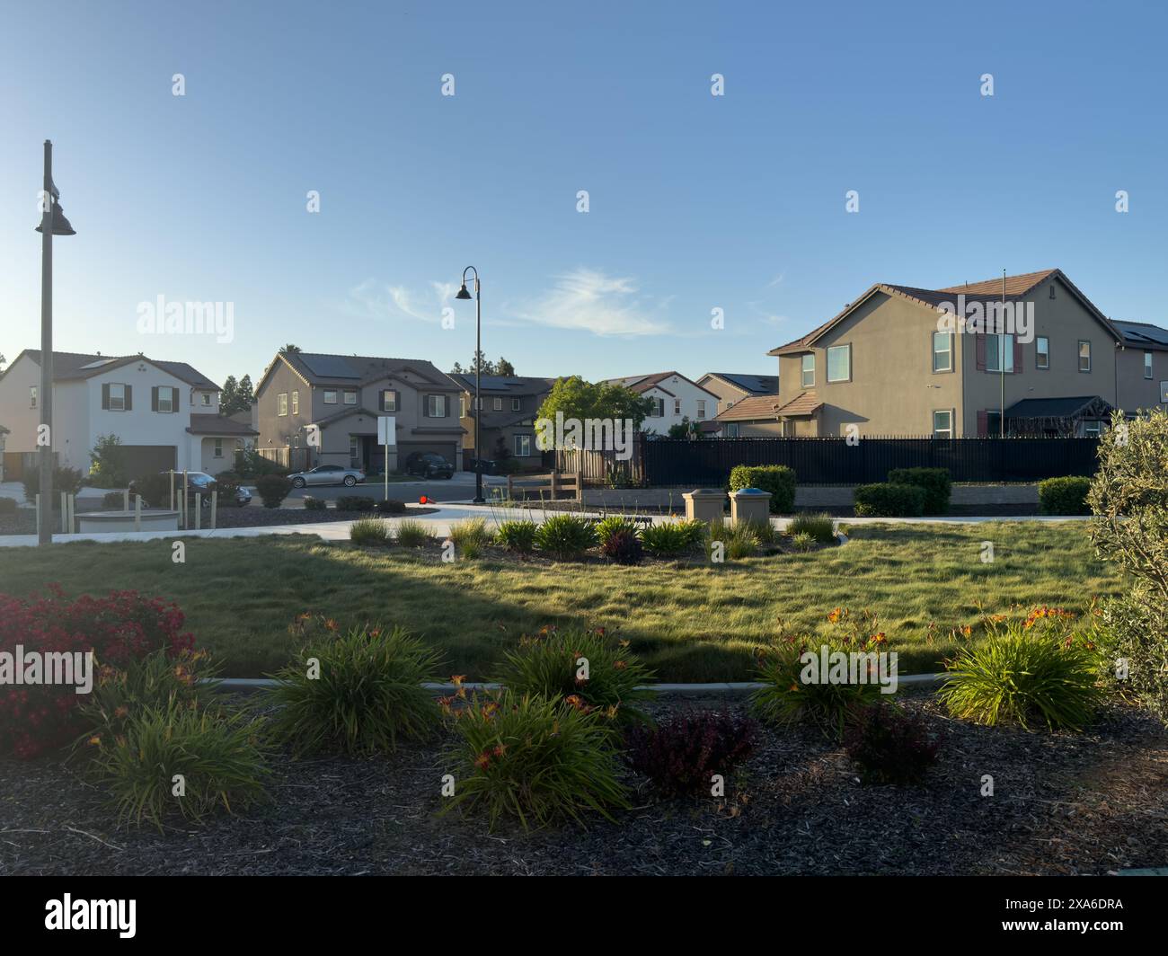 A sunny day in suburban neighborhood with houses and spacious green lawn Stock Photo