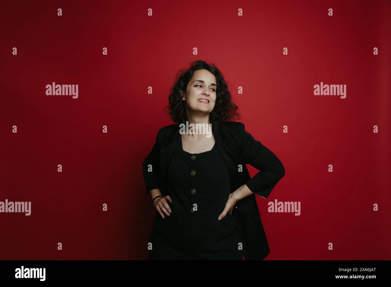 A fashionable woman posing against a vibrant red wall Stock Photo