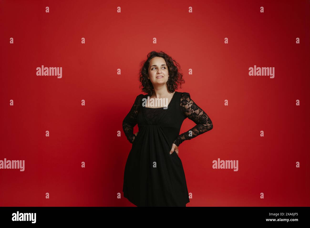 A fashionable woman posing against a vibrant red wall Stock Photo