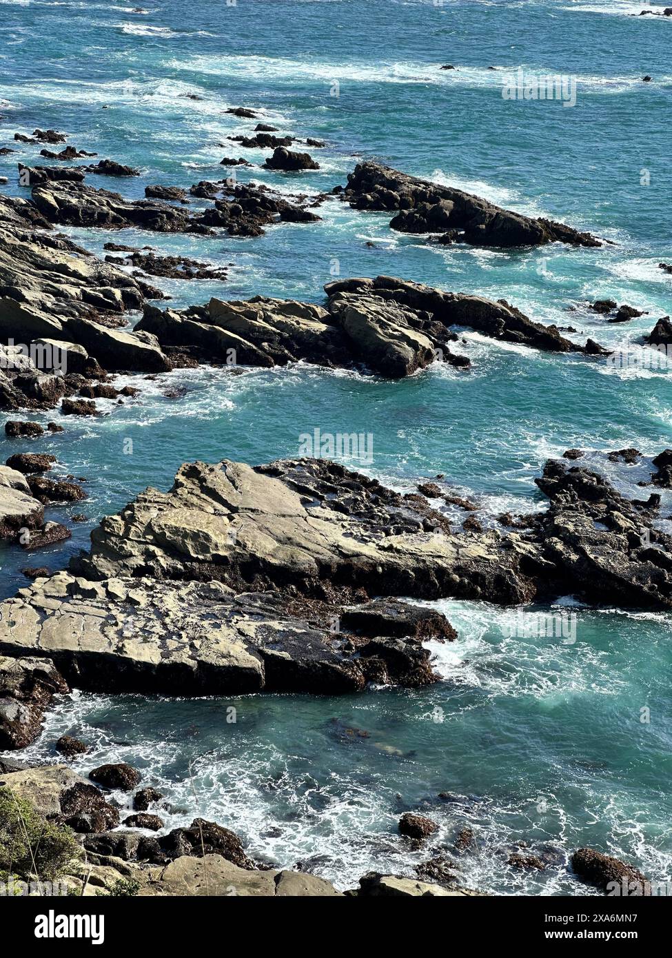 Sea rocks covered in sand with water below Stock Photo - Alamy