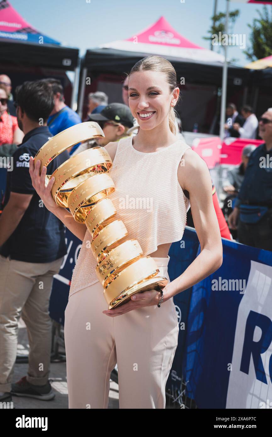 A girl in a busy street holds a sizable trophy with a large crowd in the background Stock Photo