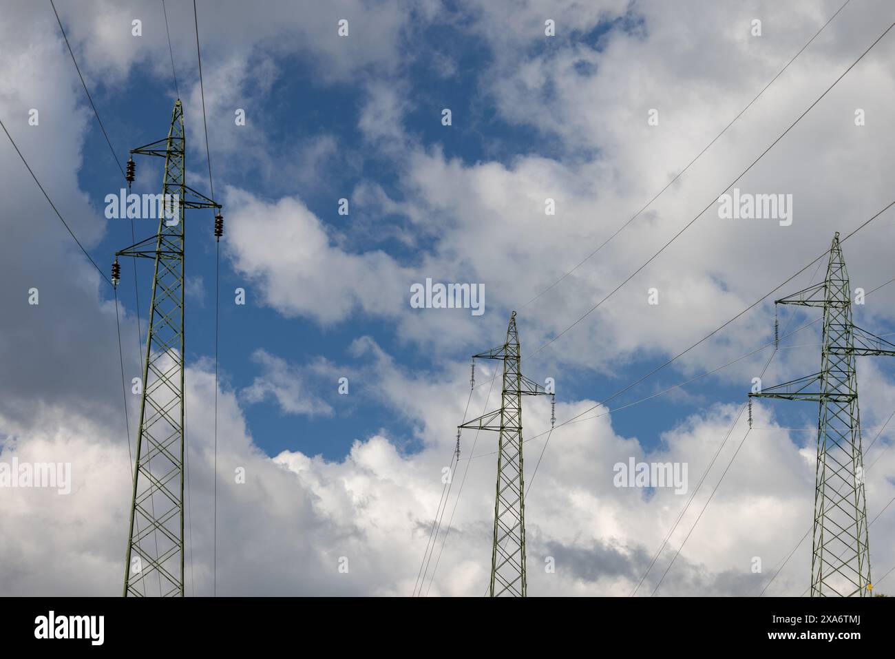 The electricity pylons under the cloudy blue sky Stock Photo - Alamy
