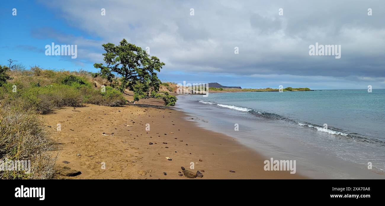 A scenic view of a deserted beach and calm waters by a mountain Stock Photo