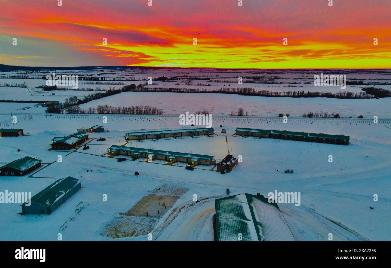 A sunset setting over a snowy farm field Stock Photo