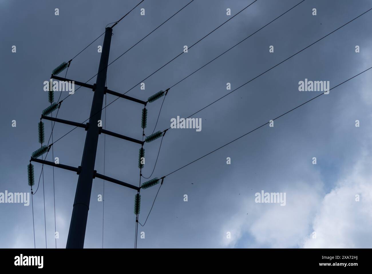 Electric pole silhouetted against dramatic cloudy sky Stock Photo