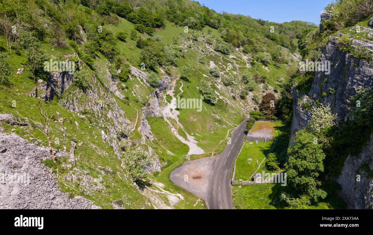 A narrow road winds through countryside alongside rocky cliffs Stock Photo