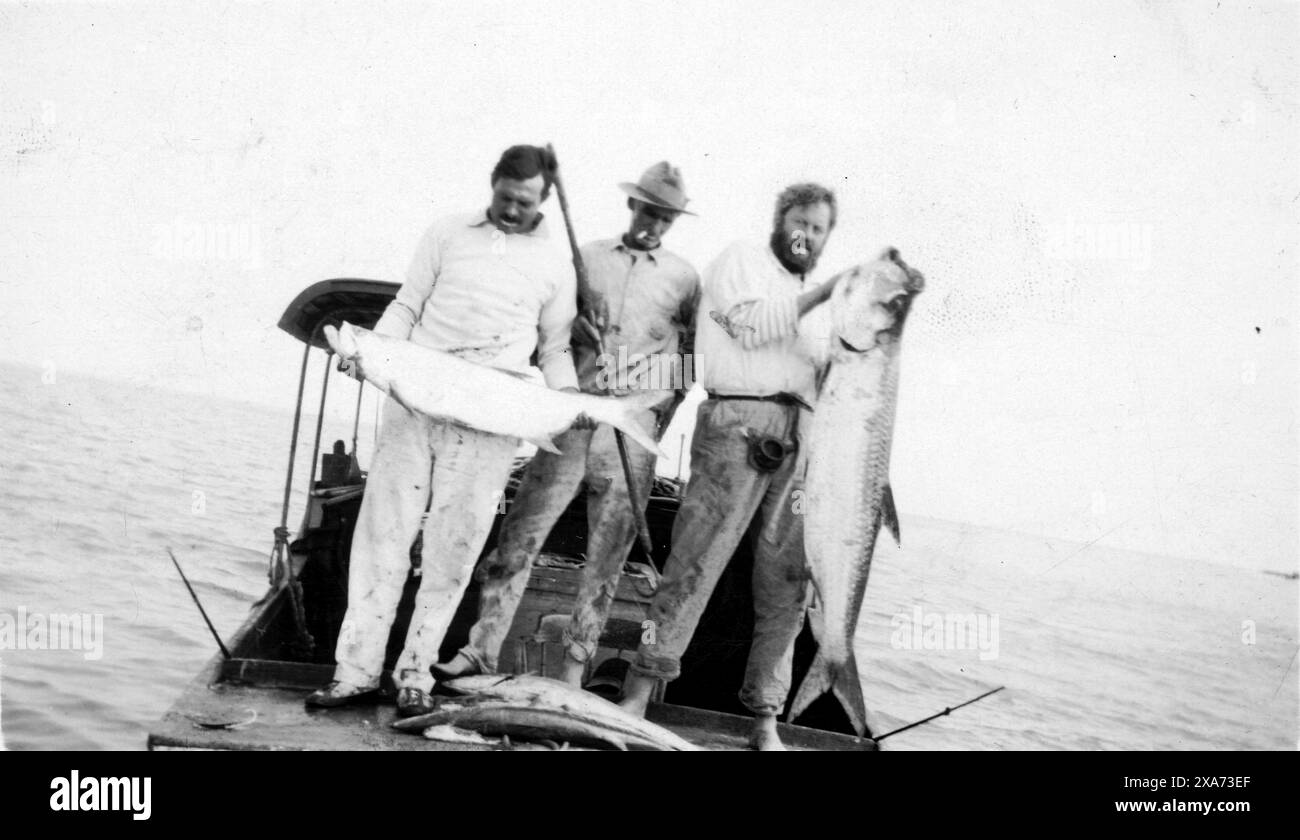 1928 Ernest Hemingway, Bra Saunders, and Waldo Peirce with fish aboard a boat near Key West, 1928.  EH's caption on the back reads, 'Papa caught both the big and the little tarpon. The big man with the beard is Waldo Pierce (sic). The small tarpon jumped 10 times out of water--shaking his head with his mouth open to get the hook out.'  Kennedy Library Stock Photo