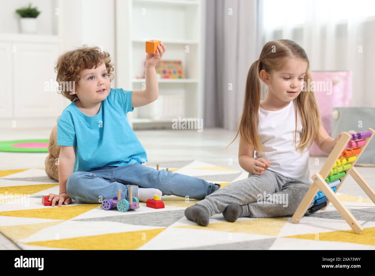 Cute little children playing with different toys on floor in ...