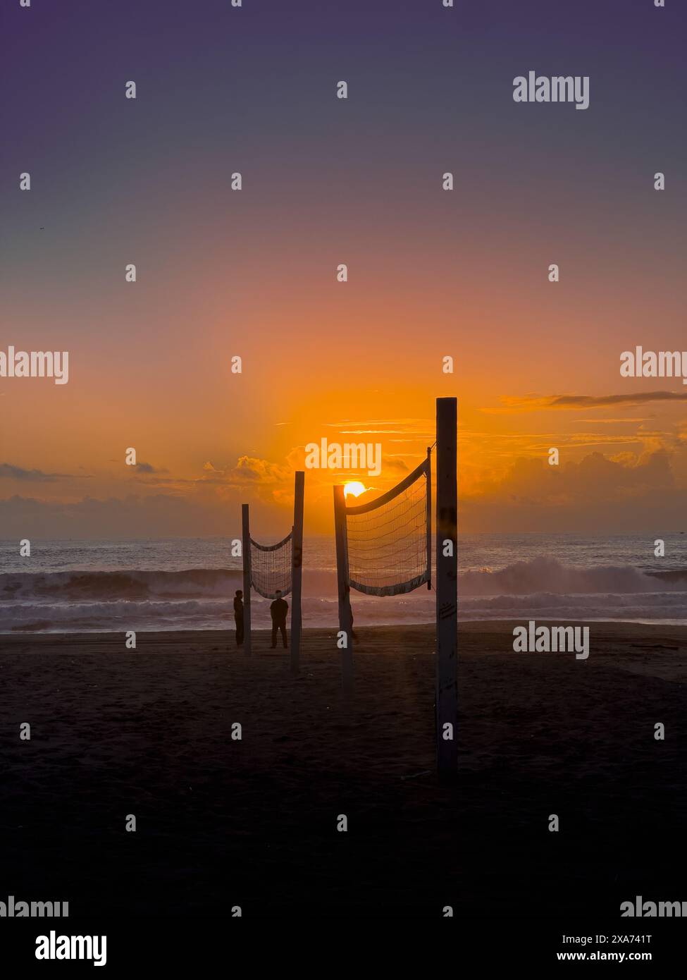 Sunset behind a beach volleyball net with people in the background