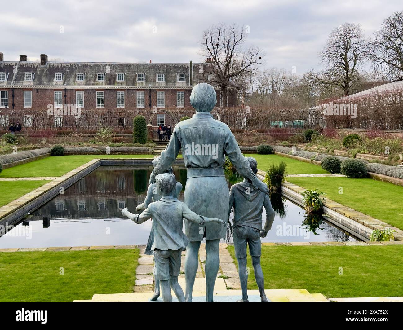 Stone sculpture of three children and an adult in a park Stock Photo