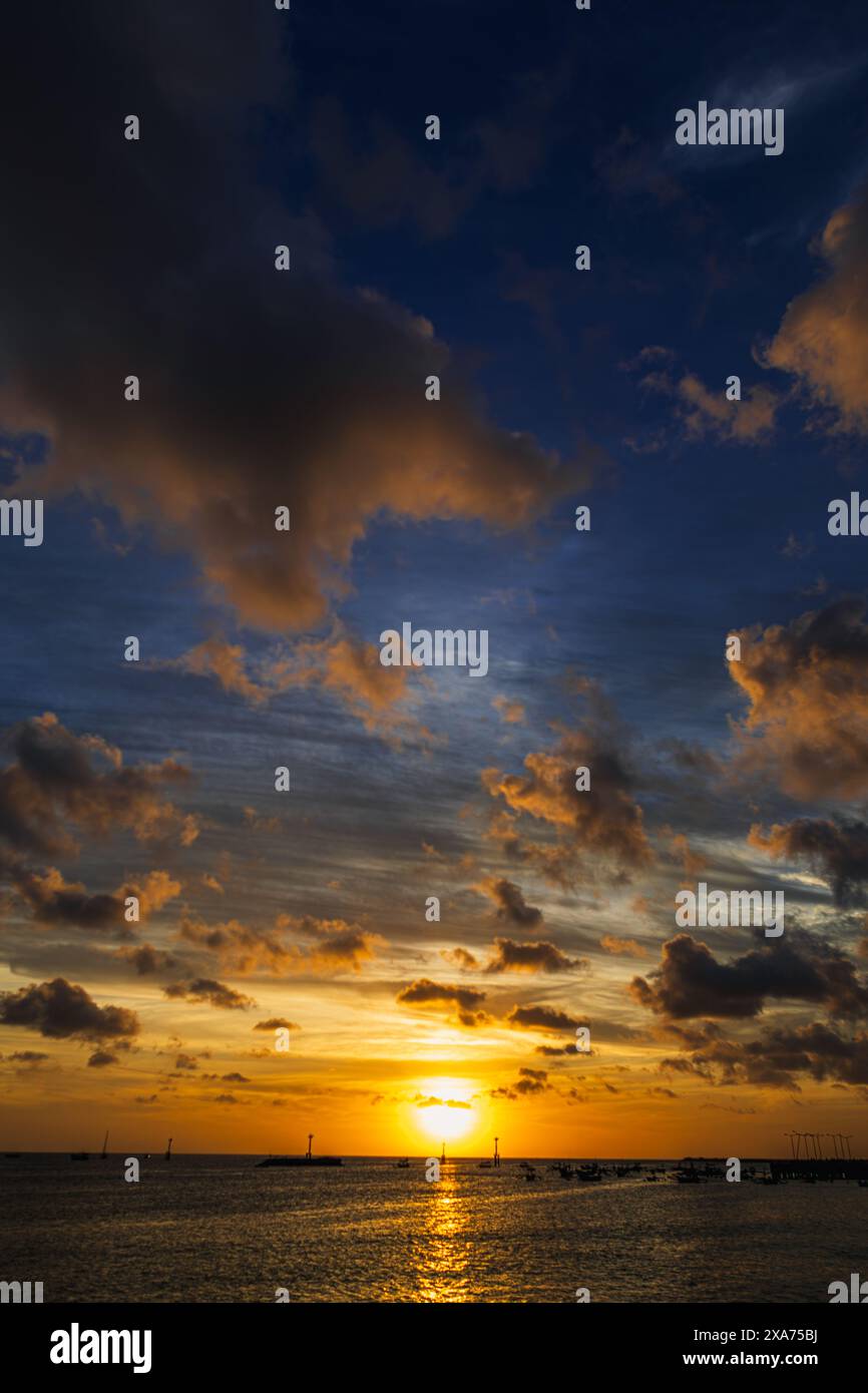 Sunset over peaceful ocean with cloudy sky Stock Photo