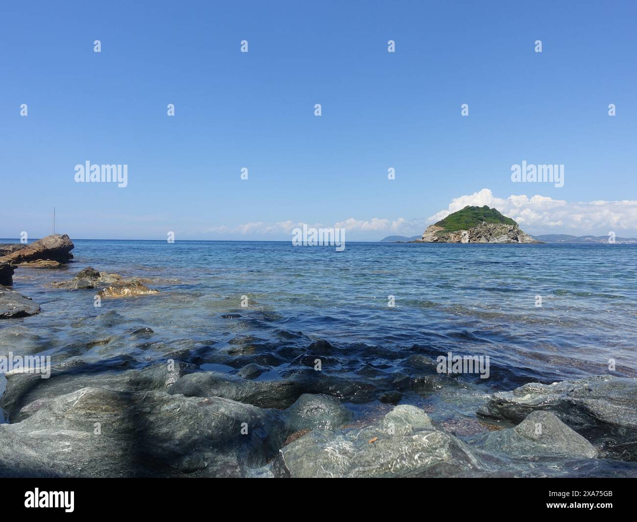A scenic view of a rocky beach against the sea on a sunny day Stock Photo