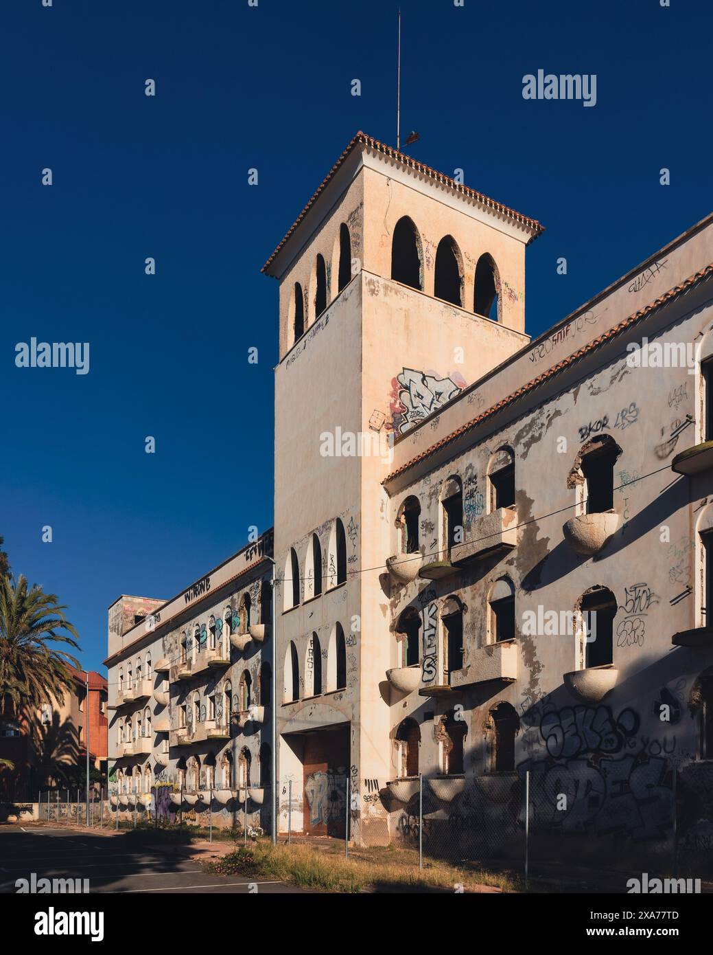 A graffiti-covered stone, abandoned, old structure with palm trees in front of it Stock Photo