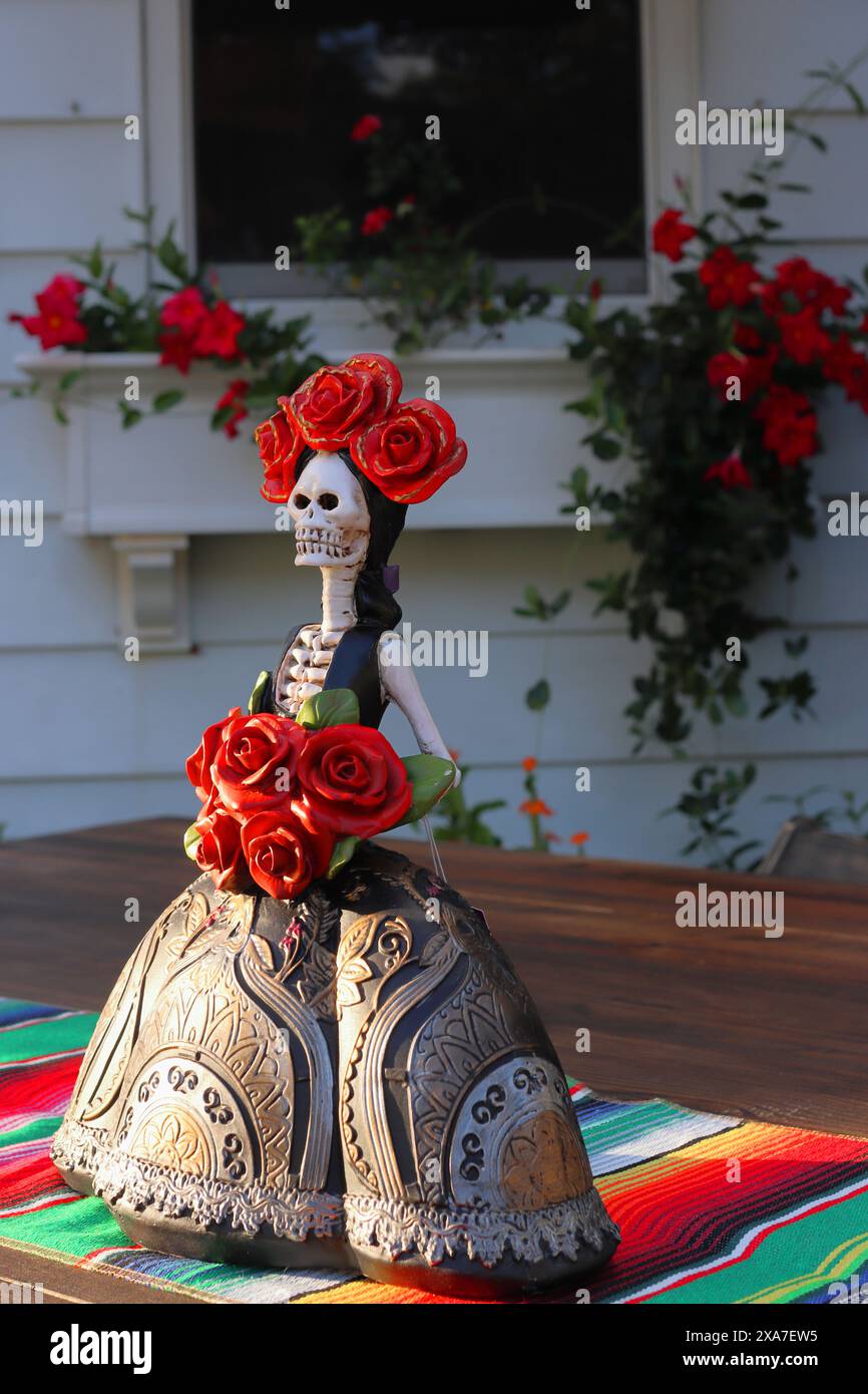 A Skull sculpture and decorative red roses on a table Stock Photo