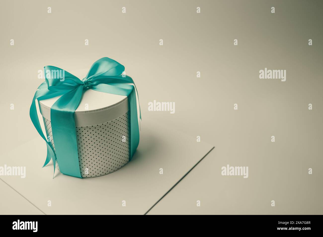 A square box with a turquoise bow atop white box Stock Photo