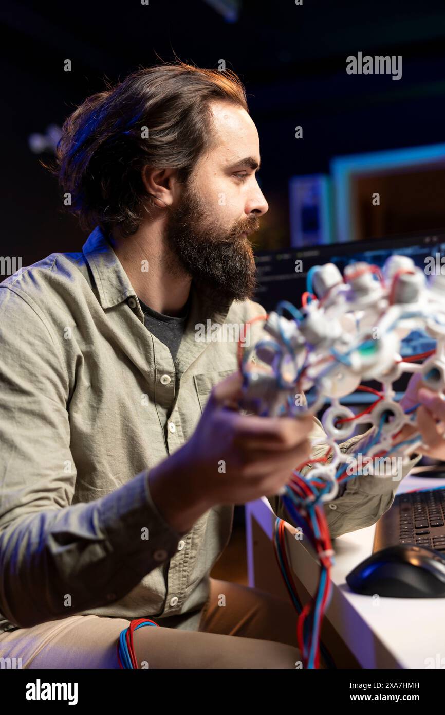 Computer scientist using EEG headset to upload his mind into computer, attaining immortality. Software developer in apartment experimenting with transferring consciousness into cyberspace Stock Photo