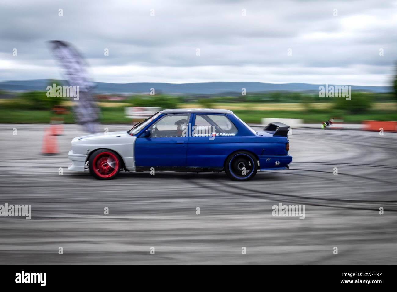 A Blue and white car maneuvering through cones on track Stock Photo - Alamy